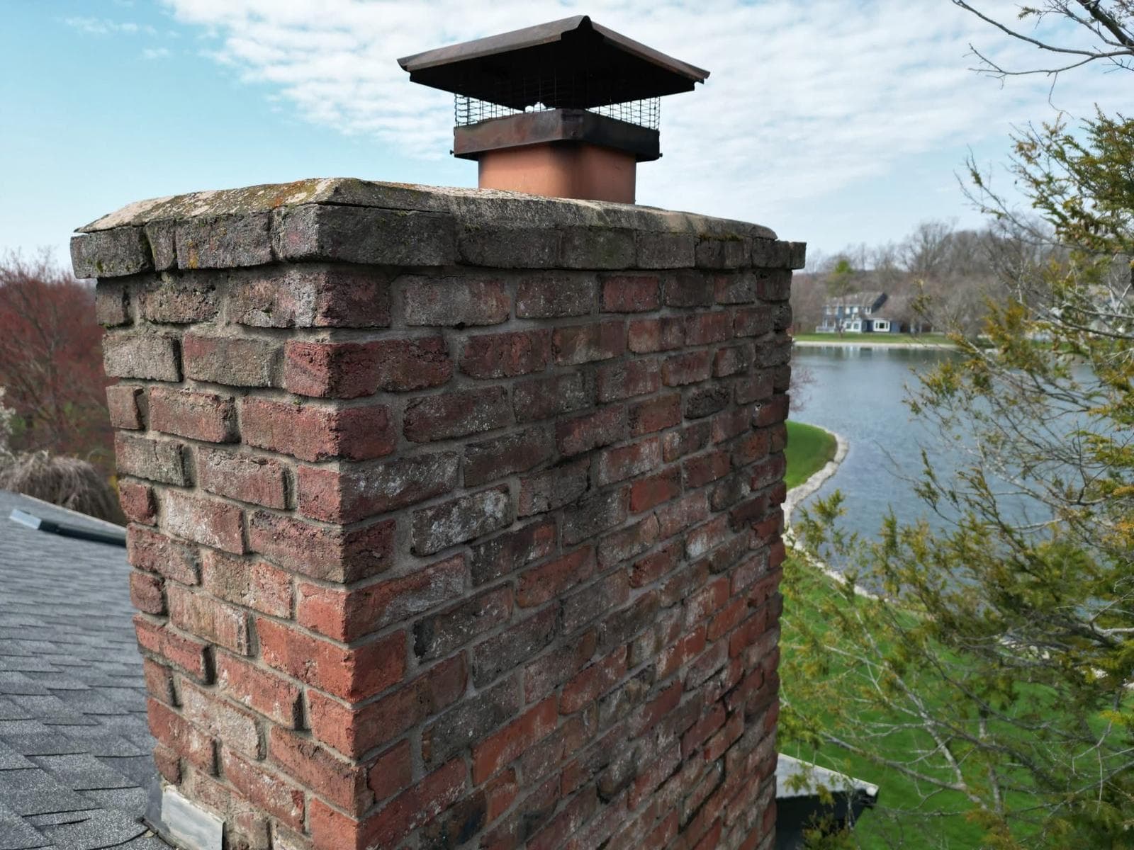 Brick chimney with a worn, cracked crown before the repair